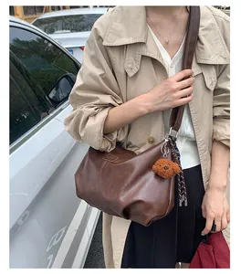 Detailed view of the brown pleated hobo bag featuring a cute plush poodle charm accessory