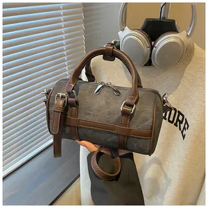 Close-up of vintage canvas Boston cylinder bag with brown leather handles and dual zippers.