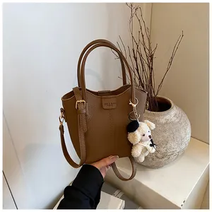 Detailed view of a brown pebbled leather bucket bag with a cute plush bear charm