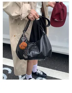 Close-up of black pleated underarm bag with poodle charm for stylish urban commute