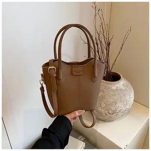 Close-up detail of the brown textured leather bucket handbag featuring dual handles