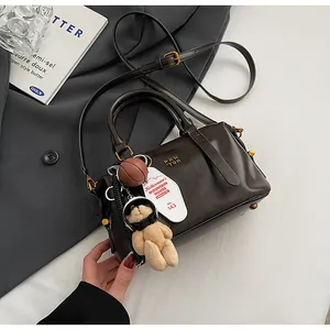 Retro dunkelbraune Boston-Tasche mit Teddybär- und Basketball-Anhängern in Nahaufnahme.