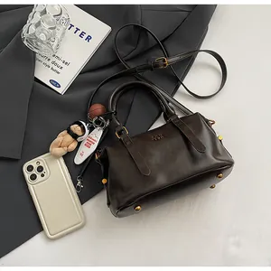 Draufsicht eines klassischen dunkelbraunen Boston-Bags mit süßem Teddybär-Anhänger