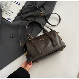 Detailansicht einer braunen Retro-Boston-Tasche mit goldenen Beschlägen und Logo