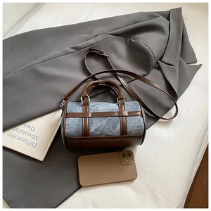Stylish blue denim and brown leather barrel bag flat lay with a grey blazer and accessories