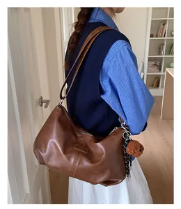 Vintage brown pleated oversized shoulder bag for college students in a casual outfit.