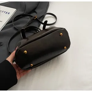 Detailansicht der Metallfüße am Boden einer dunkelbraunen Vintage-Boston-Handtasche.