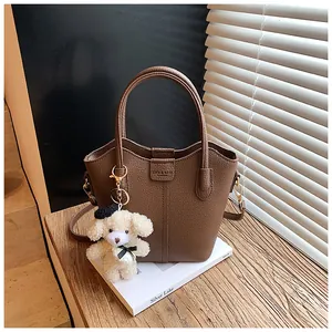Detailed view of a brown textured leather bucket bag with a cute teddy bear charm