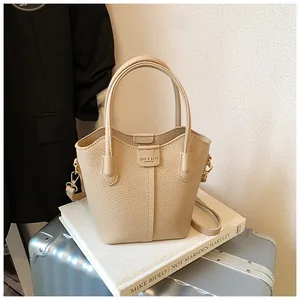 Detail of beige pebble leather bucket bag with top handles and strap on book.
