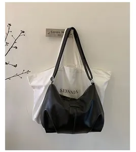 Minimalist black pleated leather underarm shoulder bag hanging on a white wall decor