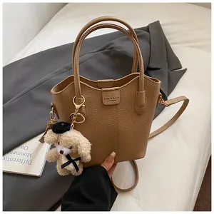 Brown textured leather bucket bag with top handle and cute teddy bear charm