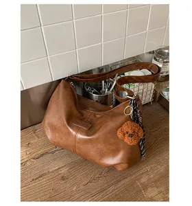Vintage brown leather pleated shoulder bag featuring a cute teddy bear charm