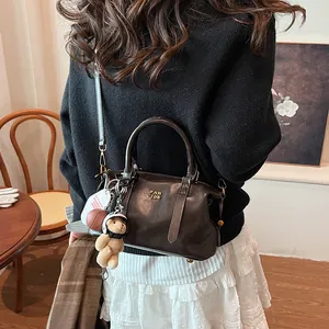Elegante braune Boston-Handtasche im Vintage-Stil mit Schultergurt und Bärenanhänger