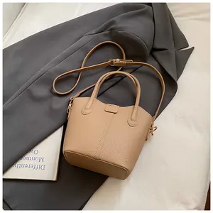 Close-up detail of tan leather bucket bag with premium textured litchi grain finish