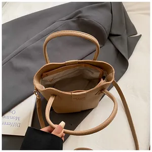 Interior detail of a stylish beige bucket bag with top handle and crossbody strap