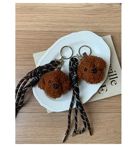 Detail view of plush poodle dog head charms with woven lanyards on a plate