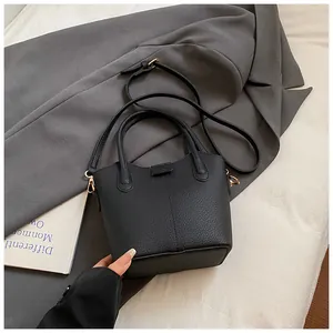 Detail view of a black pebbled leather mini bucket bag with sleek gold-tone hardware.