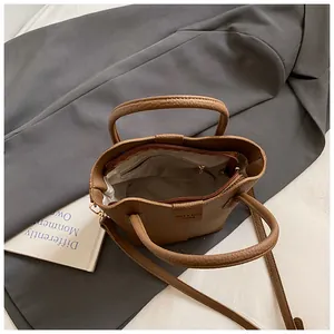 Detailed top view showing the interior and zipper pocket of a brown leather bucket bag.