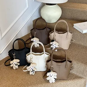 Collection of stylish pebbled leather bucket bags with teddy bear charms on stairs