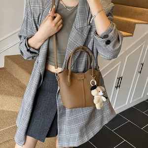 Stylish brown faux leather bucket bag featuring a cute bear keychain charm for women