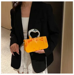 Detailed view of an orange acrylic box clutch bag featuring a heart-shaped handle and ice crack texture