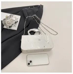 Detailed macro shot of white marble pattern acrylic box bag with elegant silver chain