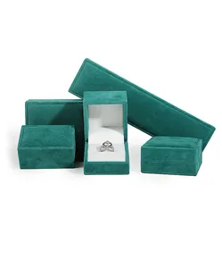 Detailed view of emerald teal velvet jewelry boxes in various sizes with a silver ring inside
