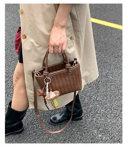 Nahaufnahme einer braun gewebten Handtasche mit einem süßen Stern- und Tieranhänger