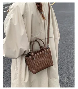 Detailansicht einer braunen geflochtenen Handtasche mit beigem Trenchcoat für Streetstyle-Look.