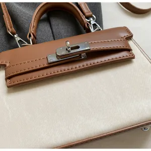 Detailansicht einer braunen Leder- und Canvas-Handtasche mit silbernem Drehverschluss.