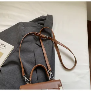 Detailansicht einer braunen Ledertasche mit Tragegriff und verstellbarem Schultergurt