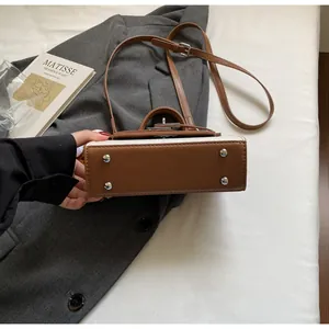 Detailansicht der Unterseite einer stilvollen braun-cremefarbenen Handtasche mit Metallfüßen