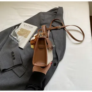 Detailansicht einer braun-beigen Handtasche aus Kunstleder mit süßem Plüschbär-Anhänger