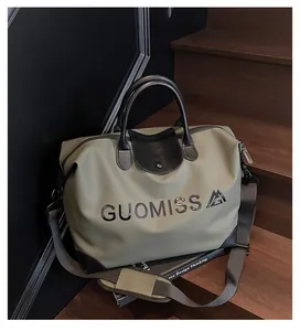 Large capacity olive travel bag with GUOMISS lettering detail on wooden stairs background
