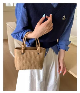 Nahaufnahme einer braun gewebten Eimertasche mit stilvollen Knotengriffen für Damen