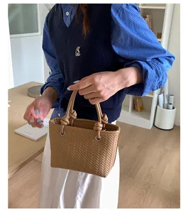 Nahaufnahme einer stilvollen braunen handgeflochtenen Ledereimertasche von einem Model.