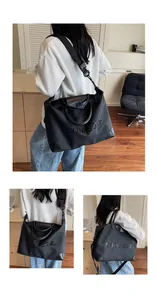 Lifestyle detail of large black travel bag featuring embossed letters and strap
