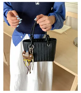 Nahaufnahme einer stilvollen schwarzen gewebten Handtasche mit süßem Bärenanhänger