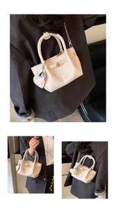 Detailed view of cream lychee texture handbag carried by a model in a stylish blazer
