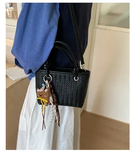 Detailansicht einer schwarzen geflochtenen Beuteltasche mit süßem Bärenanhänger