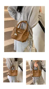 Close-up of brown litchi texture and silver chain strap on a trendy bucket handbag
