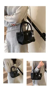 Close-up of a black pebbled leather bucket bag with elegant silver chain and charms detail
