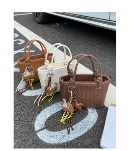 Gruppe von drei modischen gewebten Eimertaschen in verschiedenen Farben auf Asphaltboden