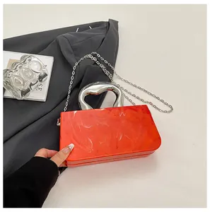 Detail shot of a stylish orange acrylic box bag with ice crack pattern and silver handle