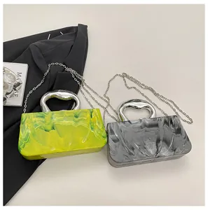Detail view showing lime green and gray marbled acrylic box clutch bags with chain strap.