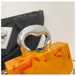 Detail of orange acrylic box bag with metallic handle and marble ice crack pattern.