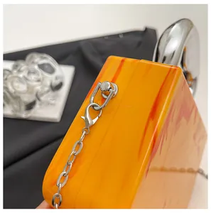 Detailed close-up of orange ice-crack pattern acrylic box bag with silver chain