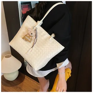 Elegante cremeweiße geflochtene Tragetasche mit süßem Bärenanhänger und Streifen.
