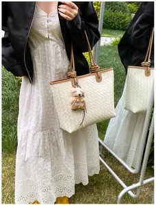 Elegante cremefarbene gewebte Tragetasche für Damen mit süßem Bärenanhänger im Garten