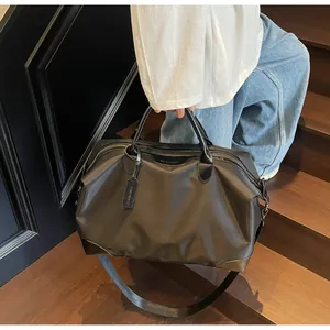 Détail d'un sac de voyage noir avec poignées en cuir et étiquette sur escalier.